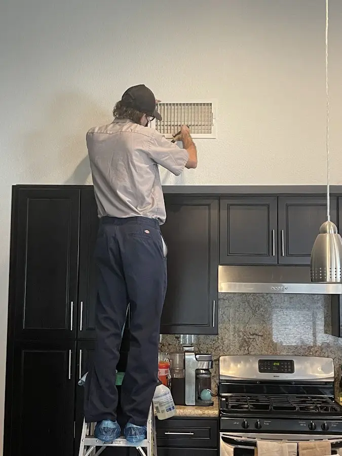 Technician inspecting an air vent during HVAC service in Roxboro